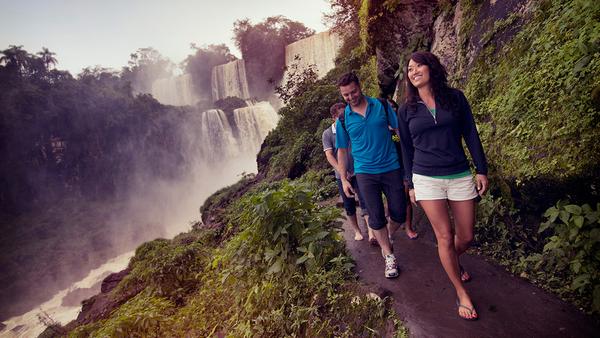 Girl walking with group on a path below the beautiful iguassu falls in argentina