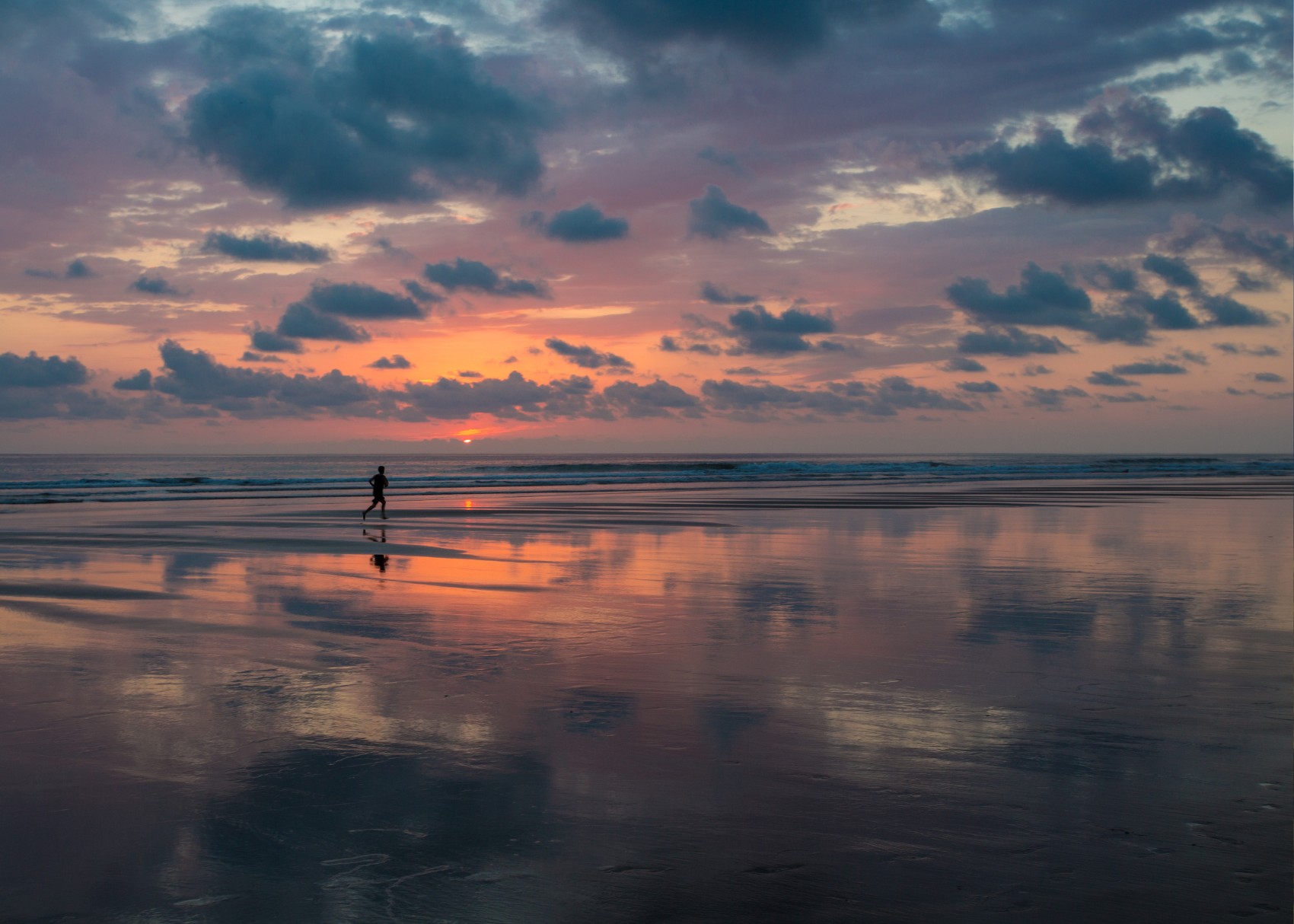 a runner chases the endless waves along Matapalo Beach after sunset