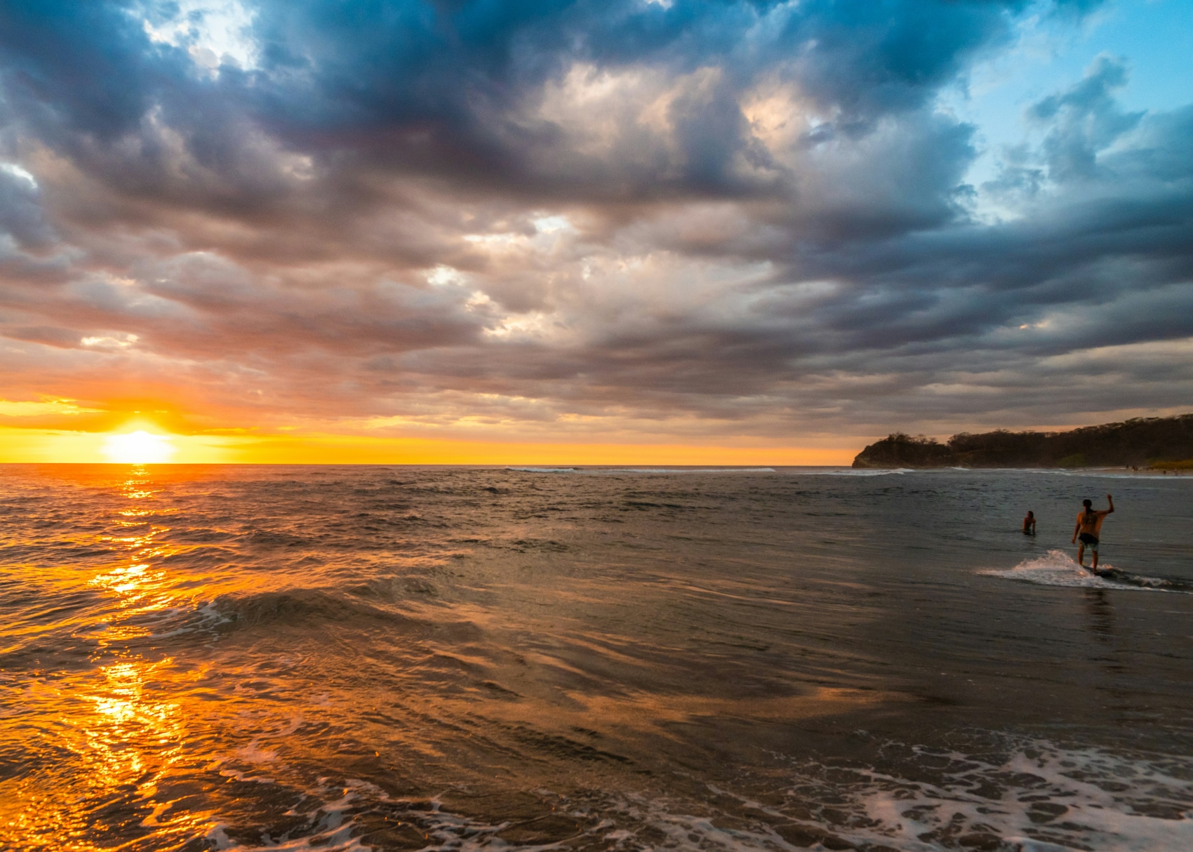 a solo male traveller surfs as the sun sets on Nosara Beach