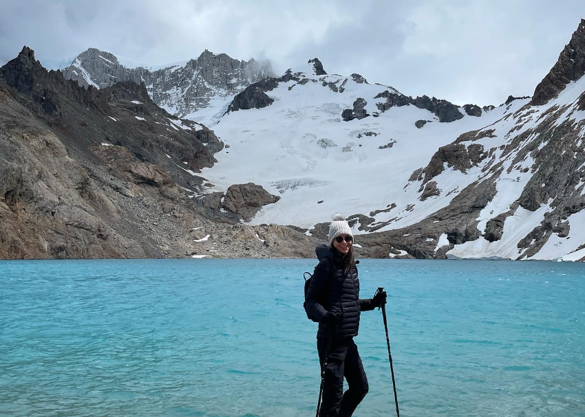 writer and traveller Jessica Moy stands in front of the iconic blue water lagoons and snow-capped peaks of Patagonia